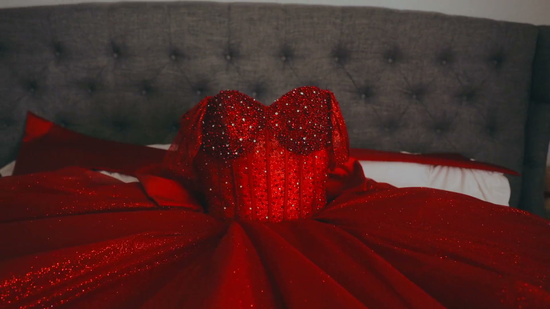 Red rhinestone quinceañera gown spread across a bed before the celebration